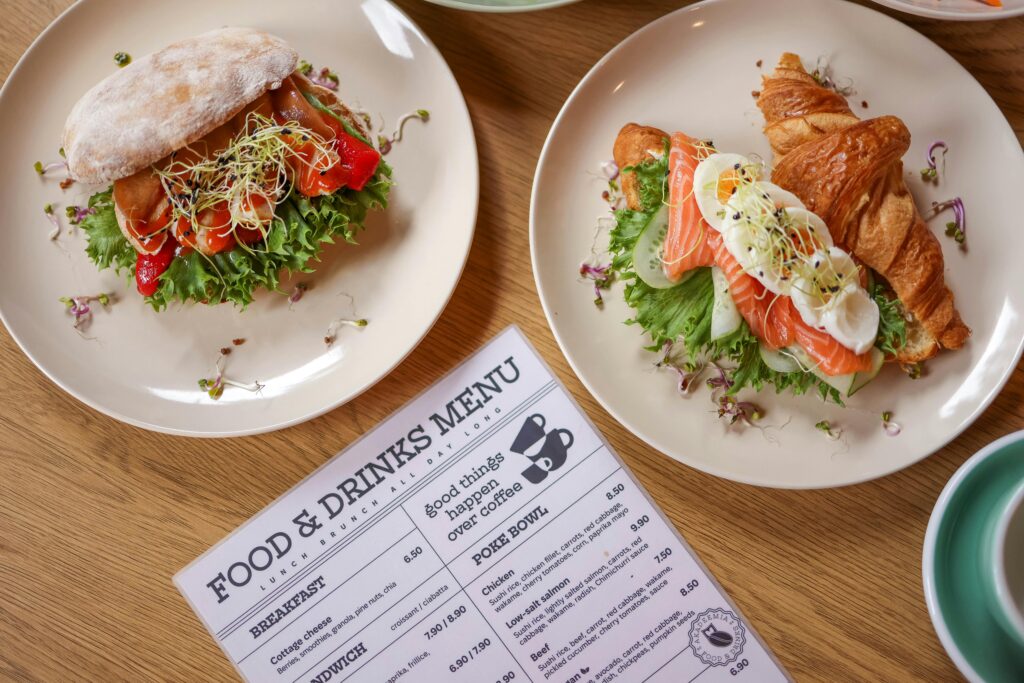 Top view of delicious salmon croissant and sandwich with fresh ingredients on wooden table.